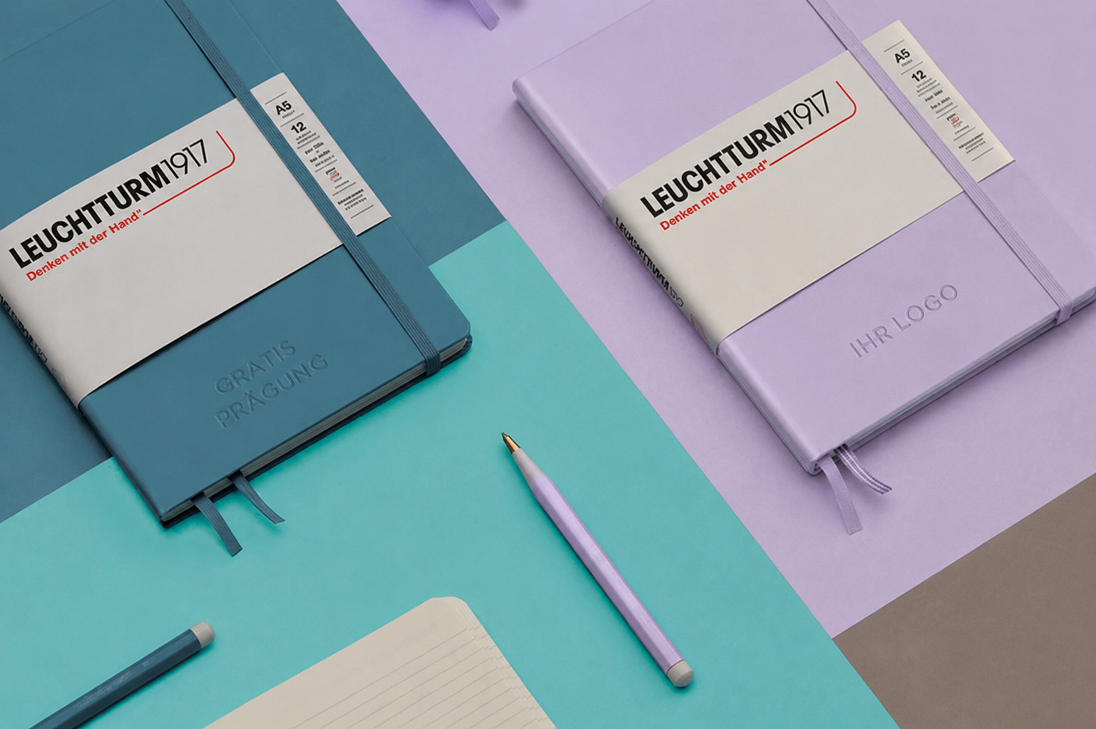 Zwei Leuchtturm1917 Notizbücher in trendigen Farbtönen mit gratis Blindprägung und individuellem Logo auf modernem Hintergrund inszeniert.